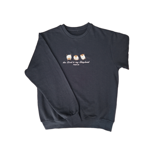 Full front view of a navy blue crewneck sweatshirt with high-quality custom embroidery of 3 fluffy white and brown sheep above the scriptures "the Lord is my Shepherd Psalm 23" in white thread.