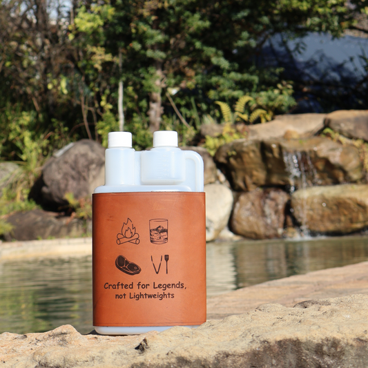 1L plastic squeezy bottle with brown leather sleeve featuring camping or braai designs, near a small waterfall in a natural setting