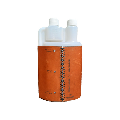 Back view of 1L squeezy bottle showing brown leather sleeve stitched in a black cross pattern, on white background