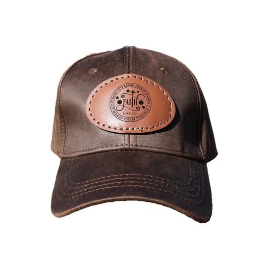 Brown oilskin cap with a leather patch engraved with Luke 1:37 Bible verse, displayed on a white background.