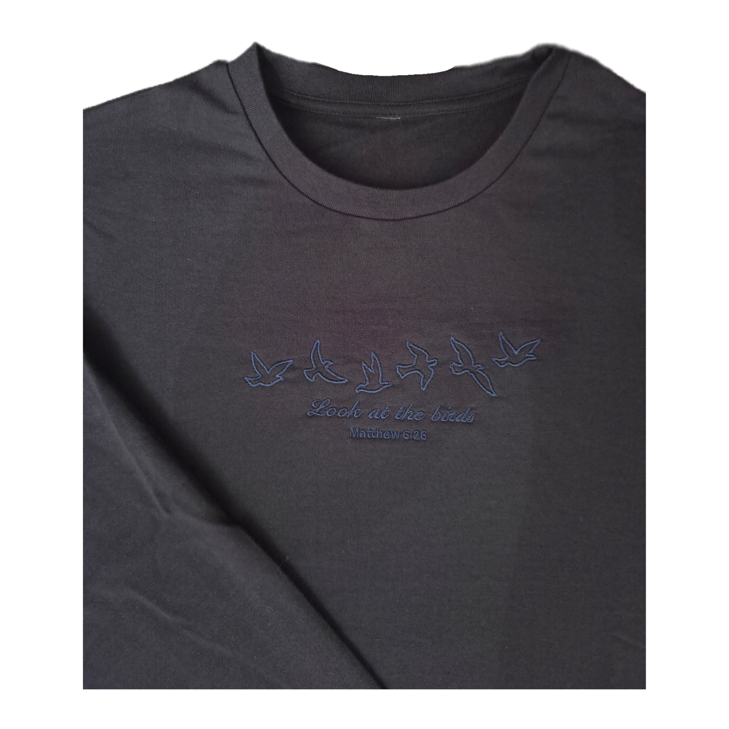 Close-up shot of the high-quality, tone-on-tone dark blue embroidery on a navy sweatshirt, showcasing the detailed satin stitching of six flying birds and the scripture "Look at the birds Matthew 6:26" in elegant cursive.