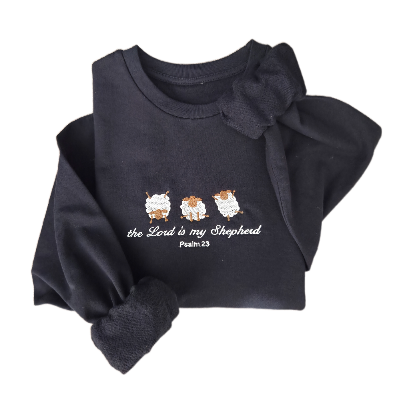 Flat lay product shot of a navy blue embroidered sweatshirt featuring three white sheep and cursive text reading "the Lord is my Shepherd Psalm 23". The cozy christian jumper is artistically folded against a clean white background.